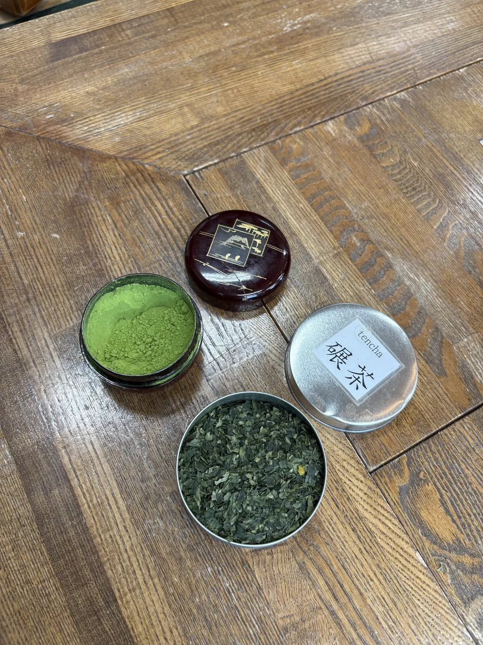 Matcha a tencha v kovových dózách vedle sebe